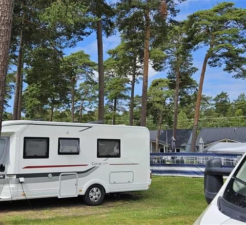 En campingplats med husvagn och cyklar parkerade utanför, som ger en känsla av utomhusaktiviteter och semester på Ystad Camping.