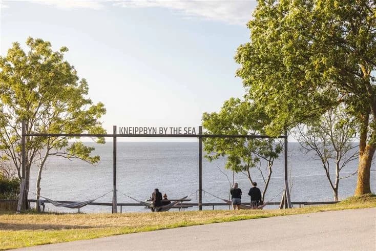 En solig dag vid Kneippbyn Resort Visby med utsikt över havet, stranden och de omgivande kustlandskapen.
