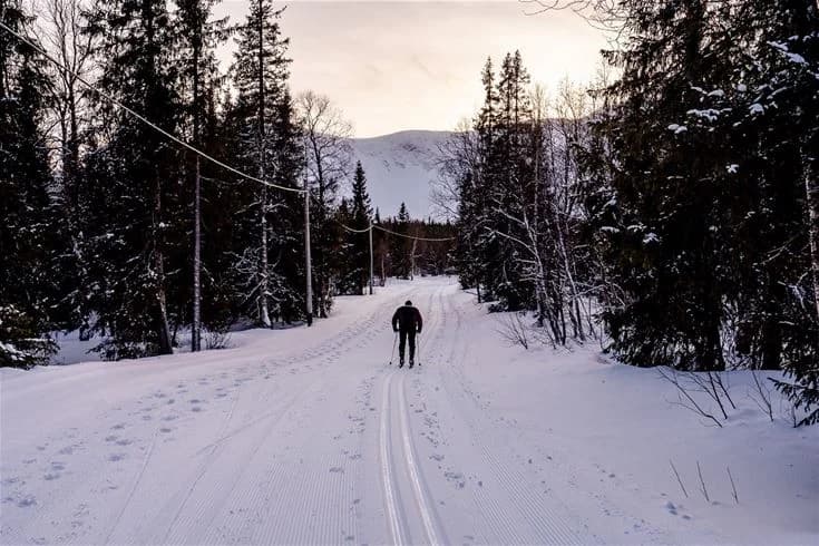 En vinterbild av Camp Kittelfjäll som visar snöbeklädda landskap och skidutrustning, omgiven av vildmark och en känsla av äventyr och utomhusrekreation i kyliga temperaturer.