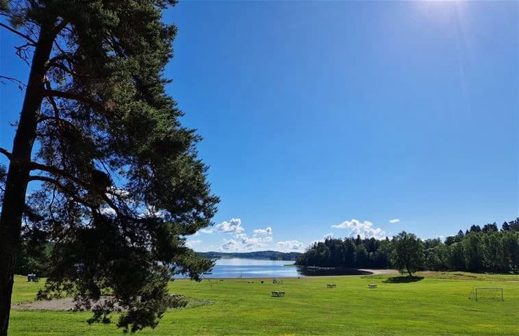 Bild av Farstanäs Camping & Havsbad med blå himmel, grönt gräs och träd i bakgrunden som skapar en naturskön miljö.