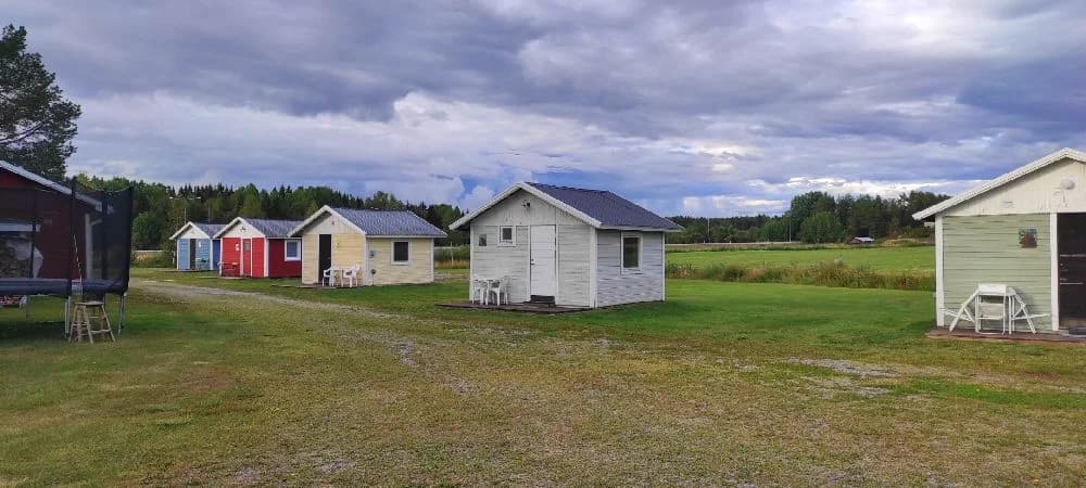 En lantlig miljö med grönskande äng och ett rött hus vid Sangis motell och camping.