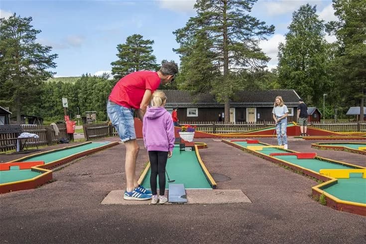 En grupp campare spelar ett spel på Älvdalens camping, omgivna av grönskande natur och lugn atmosfär.