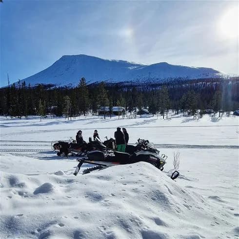 En snöig vinterlandskap vid Hede camping med snöskoteråkning på de isiga markerna. Idealisk för vinteraktiviteter och utomhusäventyr.