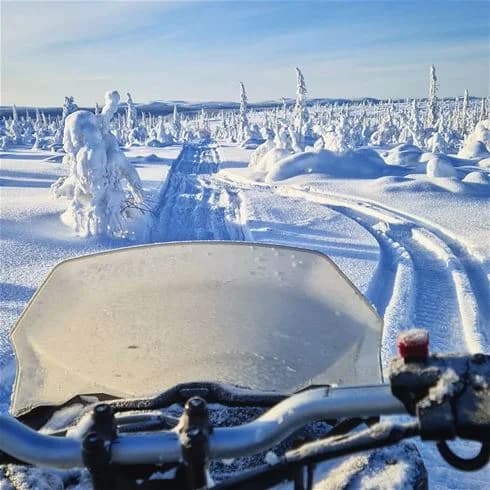 En vinterscen på Hede Camping med snöklädd mark och snöskoter, omgiven av ett istäckt landskap och arktisk tundra.