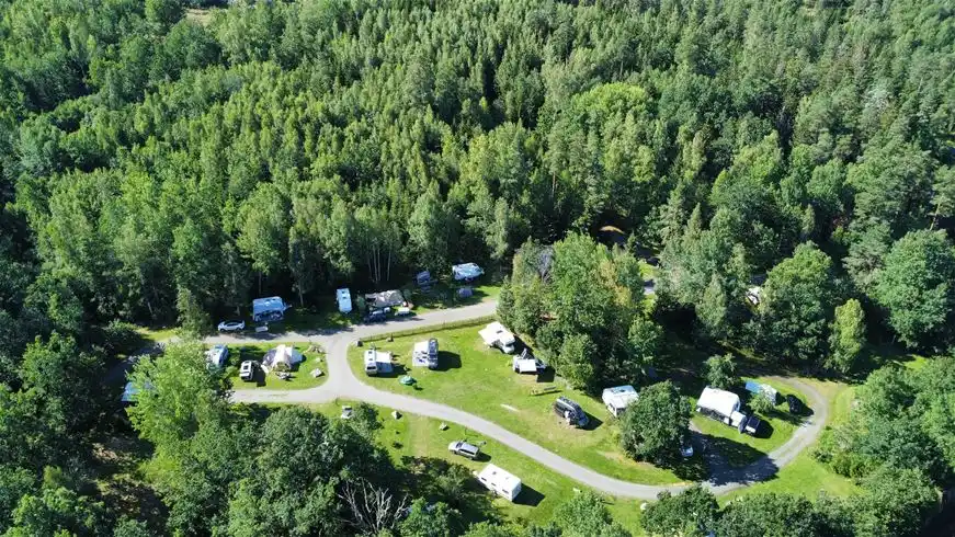 Luftfoto av Långsjön Stugor & Camping med tät skog, grönskande växtlighet och ett naturskönt landskap.