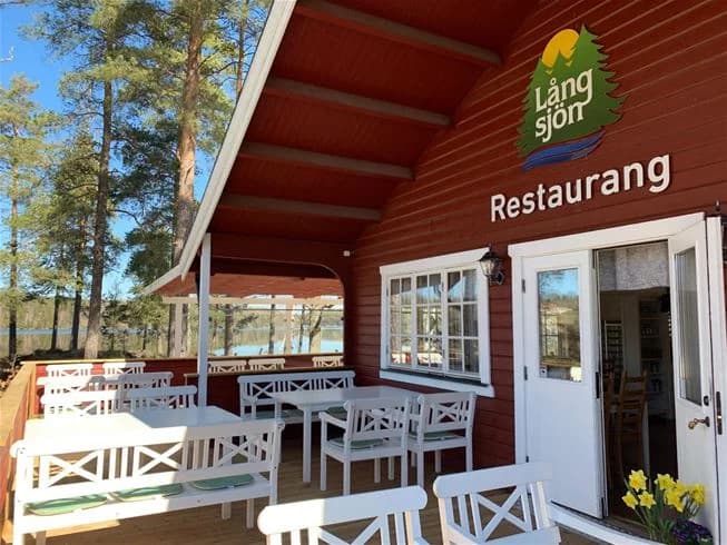 Bild av restaurangen vid Långsjön Stugor & Camping, med träbeklädnad i varm träbets. Byggnaden är i timmerstugstil och har detaljer av lövträ.