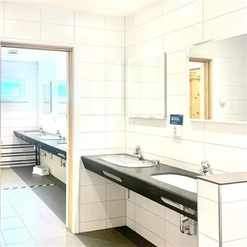 Bild av ett modernt badrum med kaklade väggar och golv. Rummet är utrustat med ett handfat, kranar och andra VVS-armaturer. Interiören signalerar en ren och funktionell design, typisk för gästboenden som stugor eller campingplatser.