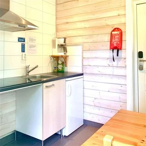 Interiörbild från Långsjön Stugor & Camping som visar ett rum med trägolv och träinredning. Möbel, dörr och inredningsdetaljer av trä skapar en varm och inbjudande atmosfär.