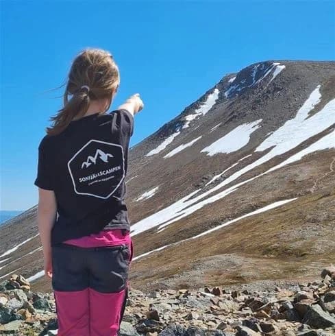 Personer vandrar genom ett snötäckt landskap vid Sonfjällscampen. De är klädda för vinterväder och njuter av en friluftsupplevelse i en naturskön miljö.
