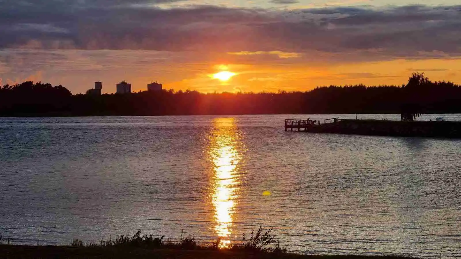 En solnedgång över en stilla sjö vid Malexander camping, med en klar himmel och vackra färger som reflekteras i vattnet.