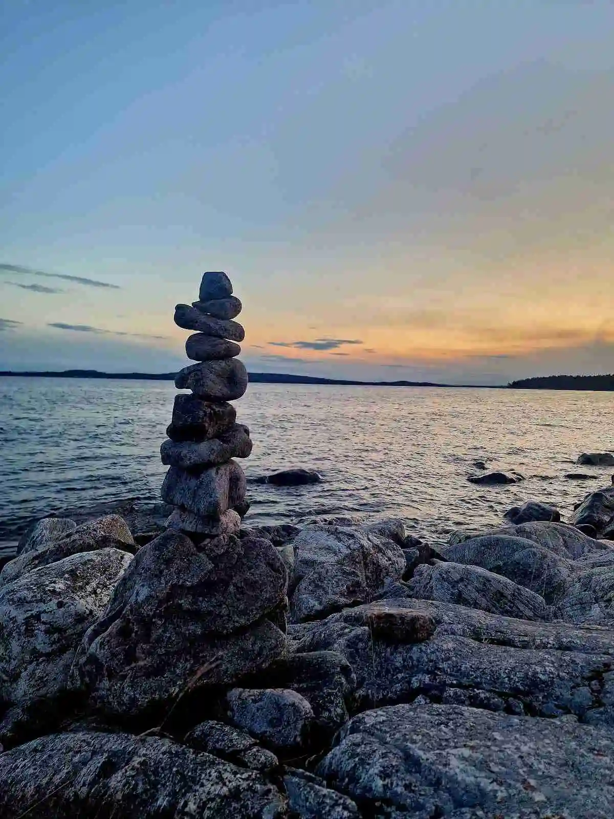 Bild av Hölick Havsresort vid skymning. En vidsträckt horisont sträcker sig över det lugna havet, med klippor som bryter av den kustnära linjen. Mjuka moln färgas av den nedgående solen mot en klar himmel.