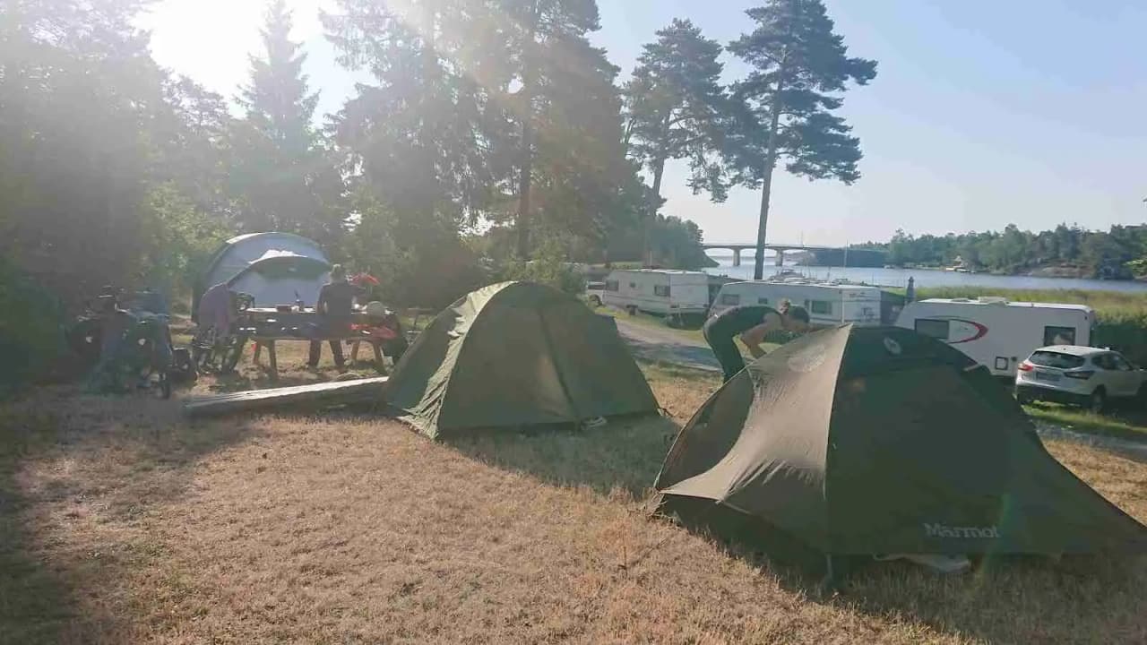 En uppställd campingplats med ett tält och campingutrustning omgiven av grönska, som visar en avkopplande och naturnära miljö för besökare på Norrtälje camping.