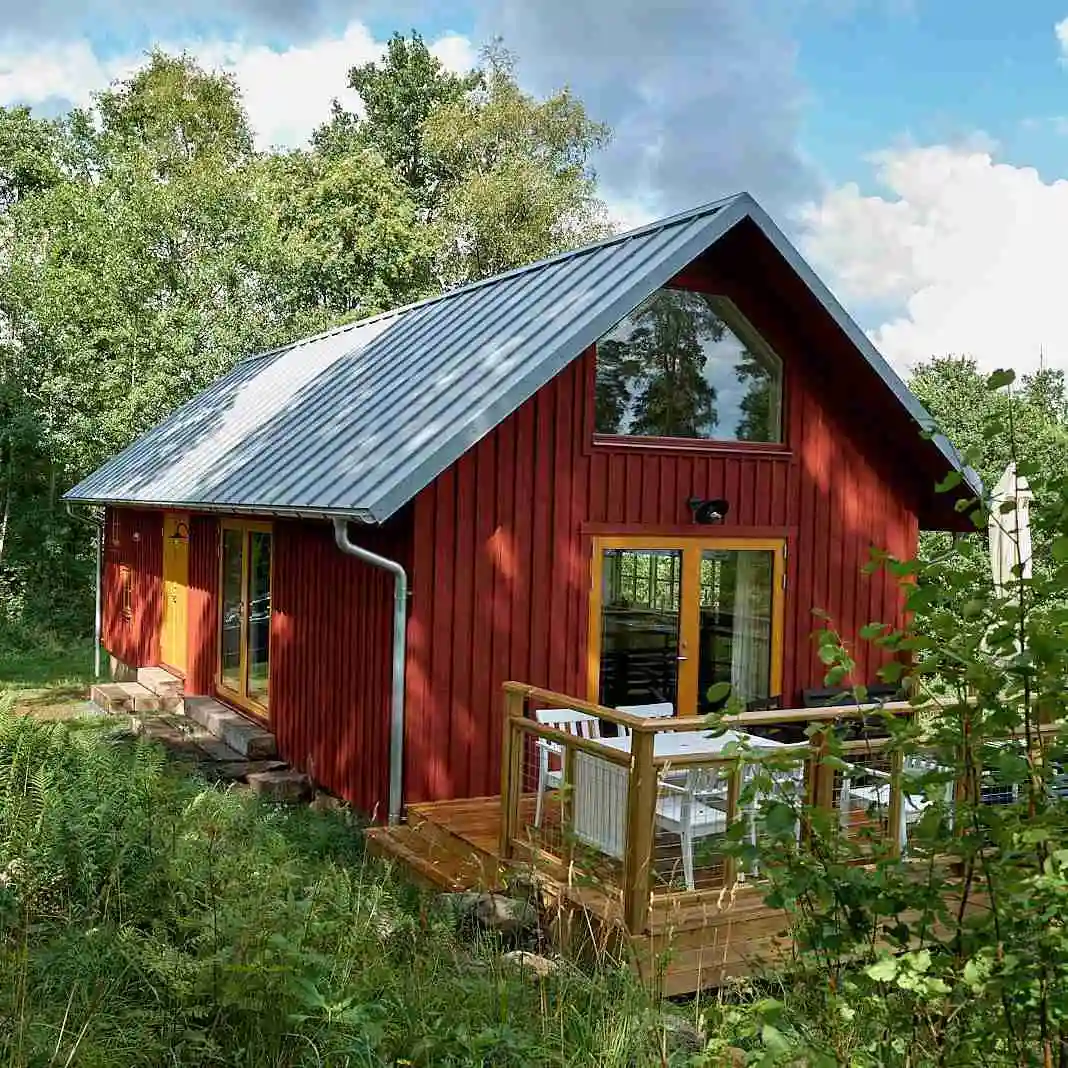 En rustik trästuga omgiven av grönska, typiskt för Agundaborg Camp & Paddle, med träfasad och ett mysigt, naturligt utseende.