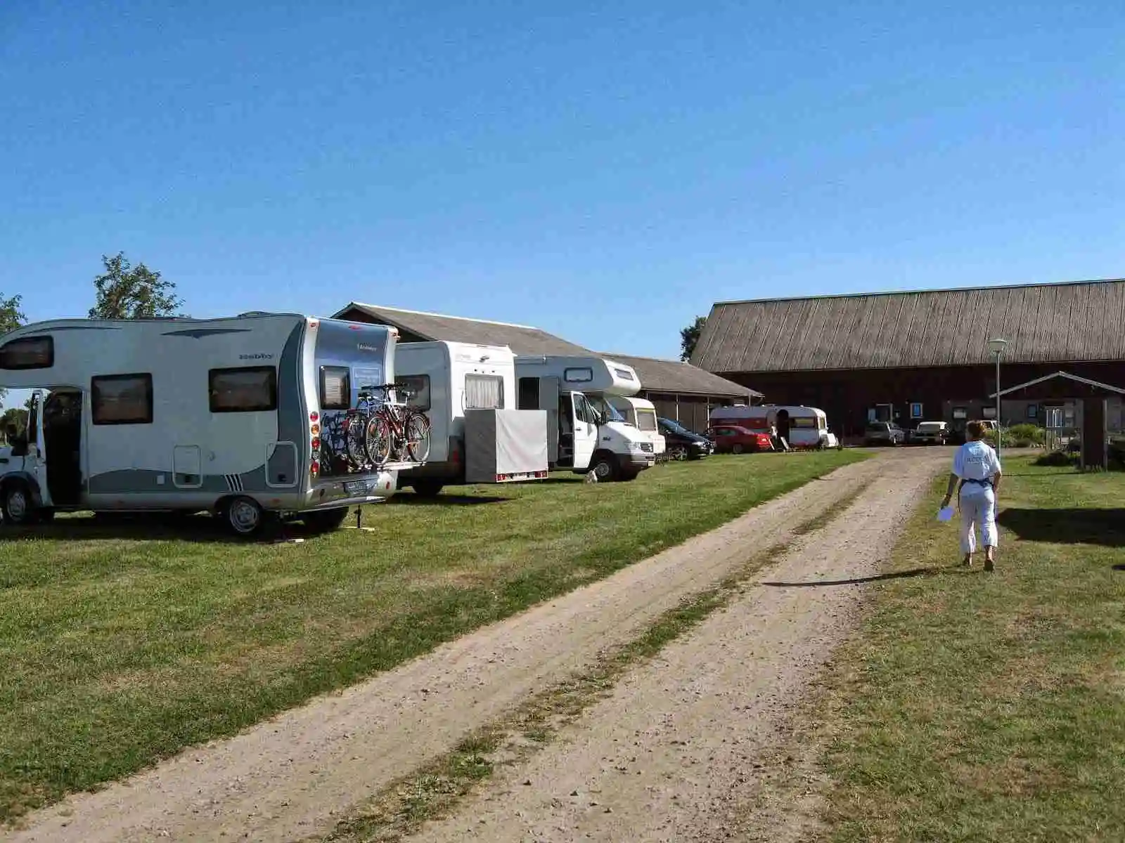 En husbil och en husvagn parkerade på en grön campingplats vid Rödlix Hostel & Camping.