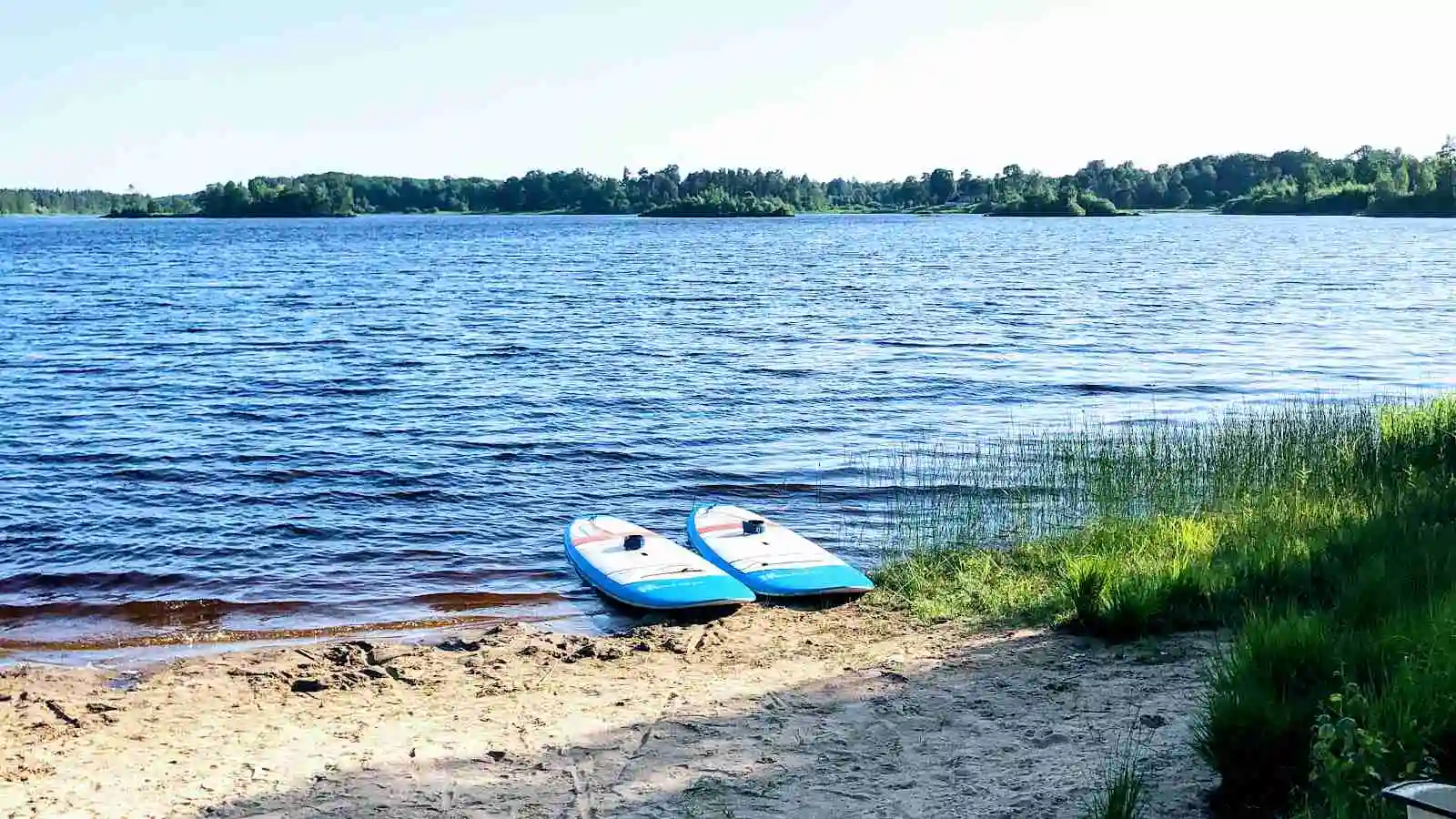 Bild av en naturskön plats vid vatten, med blått vatten och grönska runtomkring. Perfekt för sommaraktiviteter som paddling och camping vid Agundaborg Camp & Paddle.