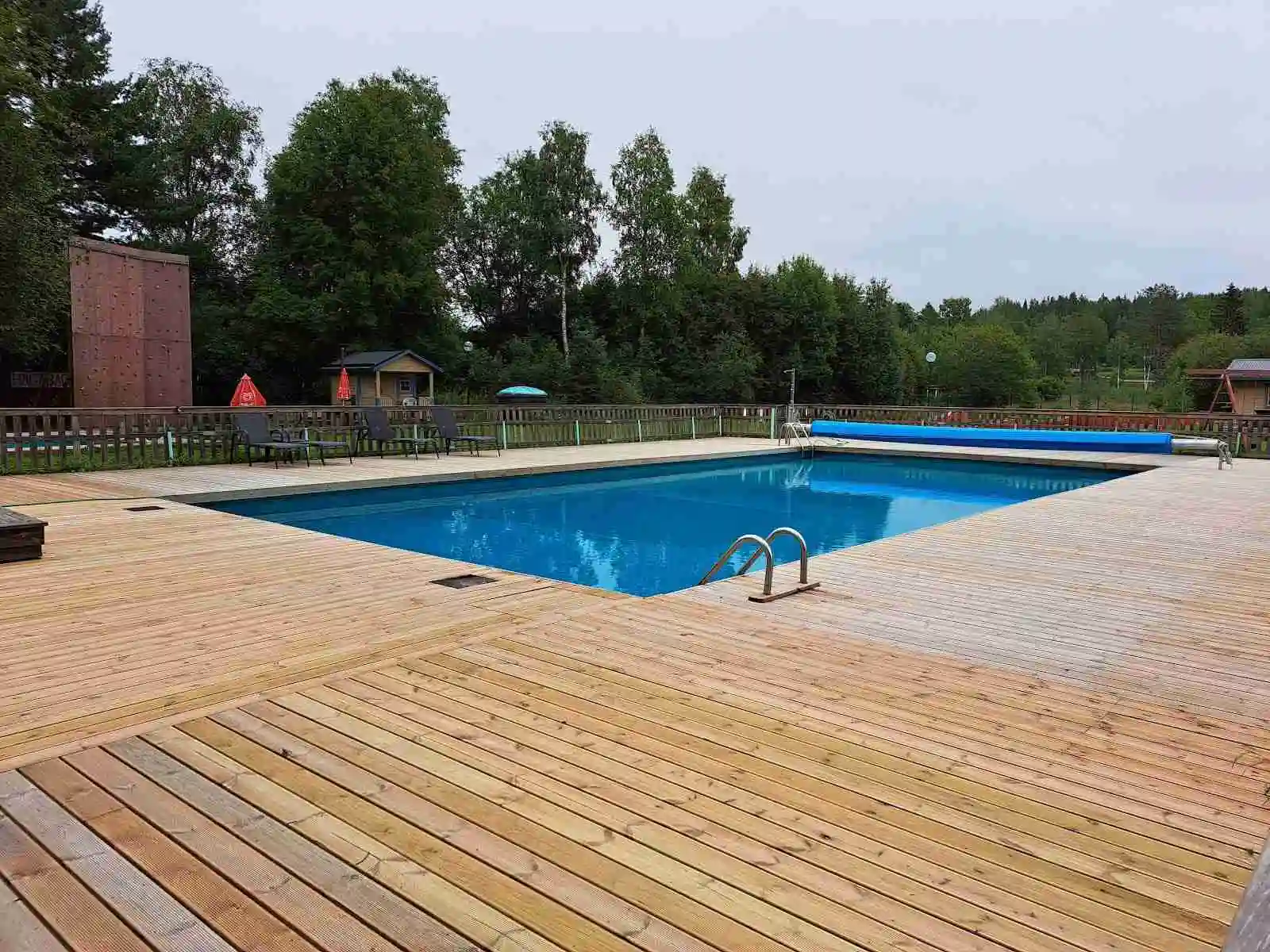 En avkopplande semesterplats med en utomhuspool omgiven av träbyggnader och grönska på Yttermalungs camping & stugby.