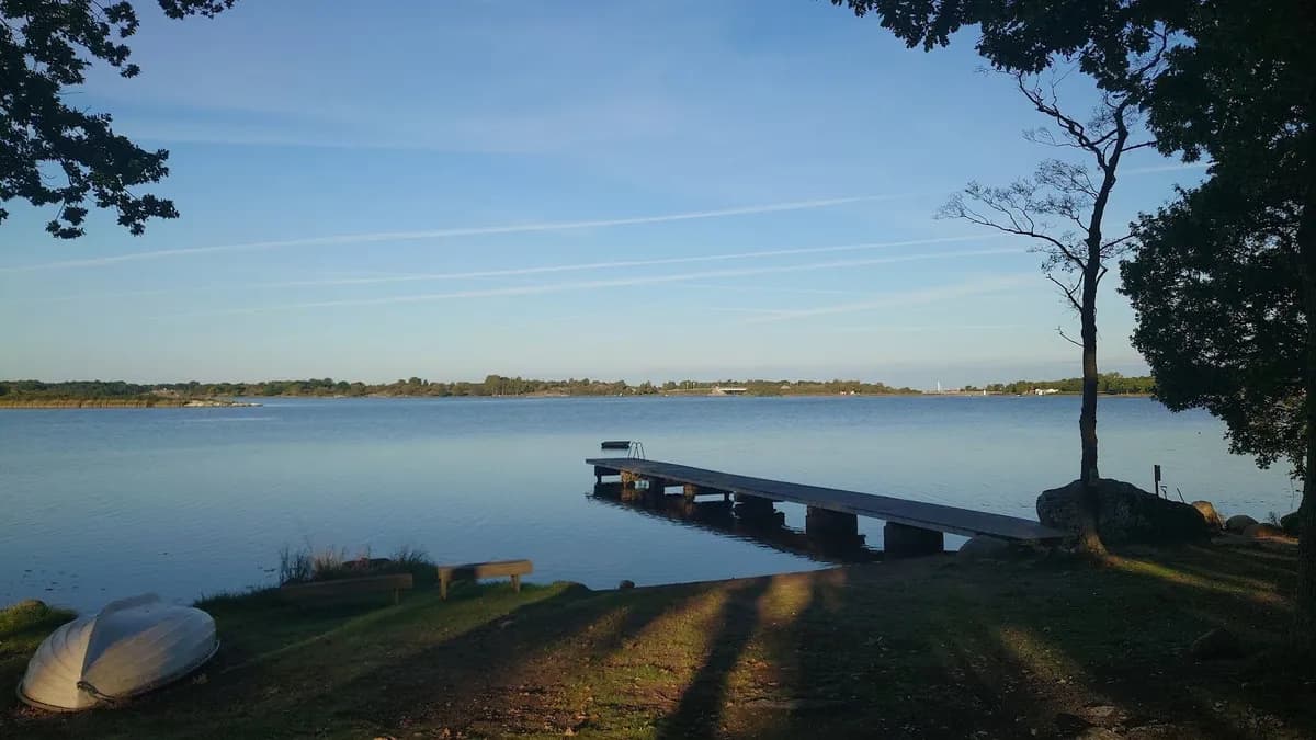 Ett naturskönt kustlandskap vid Kustgården Senoren med blå himmel och vatten i förgrunden.