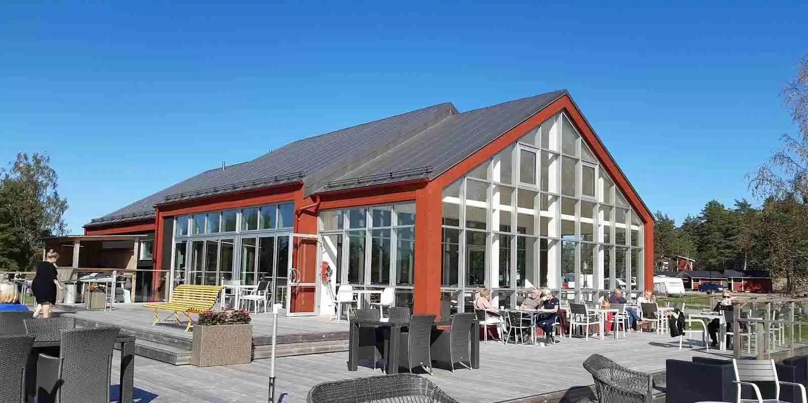 Bild av Ekenäs gästhamn & camping med vy över småbåtshamn och campingområde, omgiven av grönska och vatten.