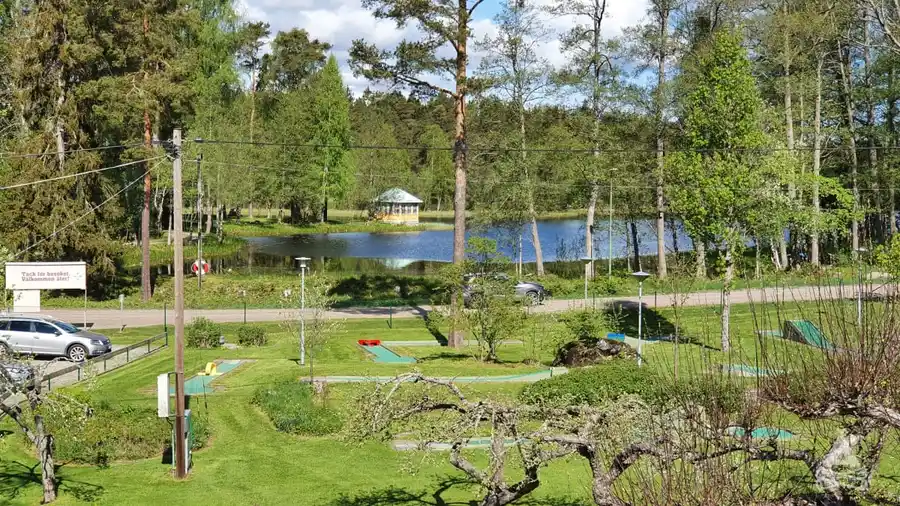 Bild av en lummig utomhusmiljö vid Sofielund Vandrarhem & Camping, med träd och växter kring en liten damm eller vattenreservoar, som skapar en fridfull och naturnära atmosfär.