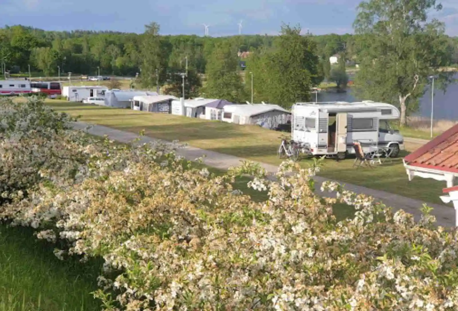 En husvagn parkerad på Vegby Camping, omgiven av grönska och flera parkeringsplatser.