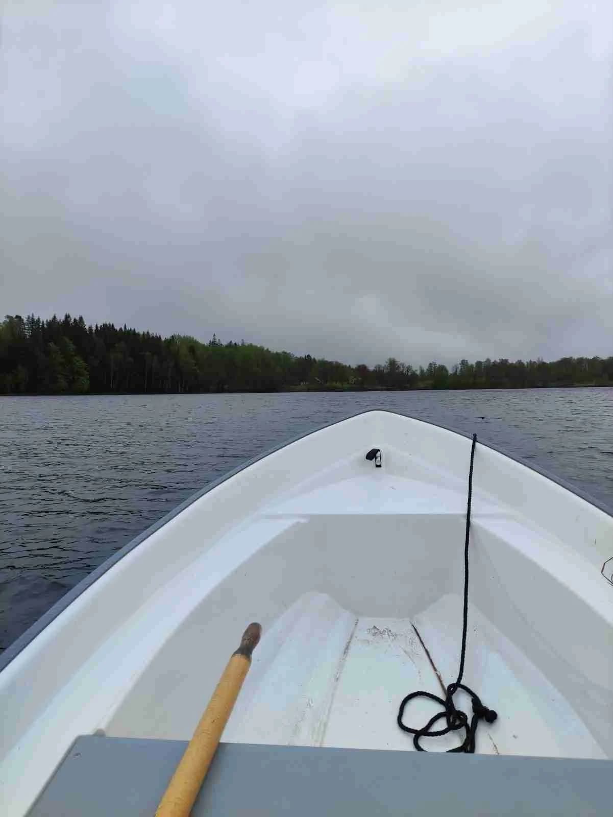 En liten båt flyter på en stilla sjö under en molnig himmel vid Kalvs Familjecamping.