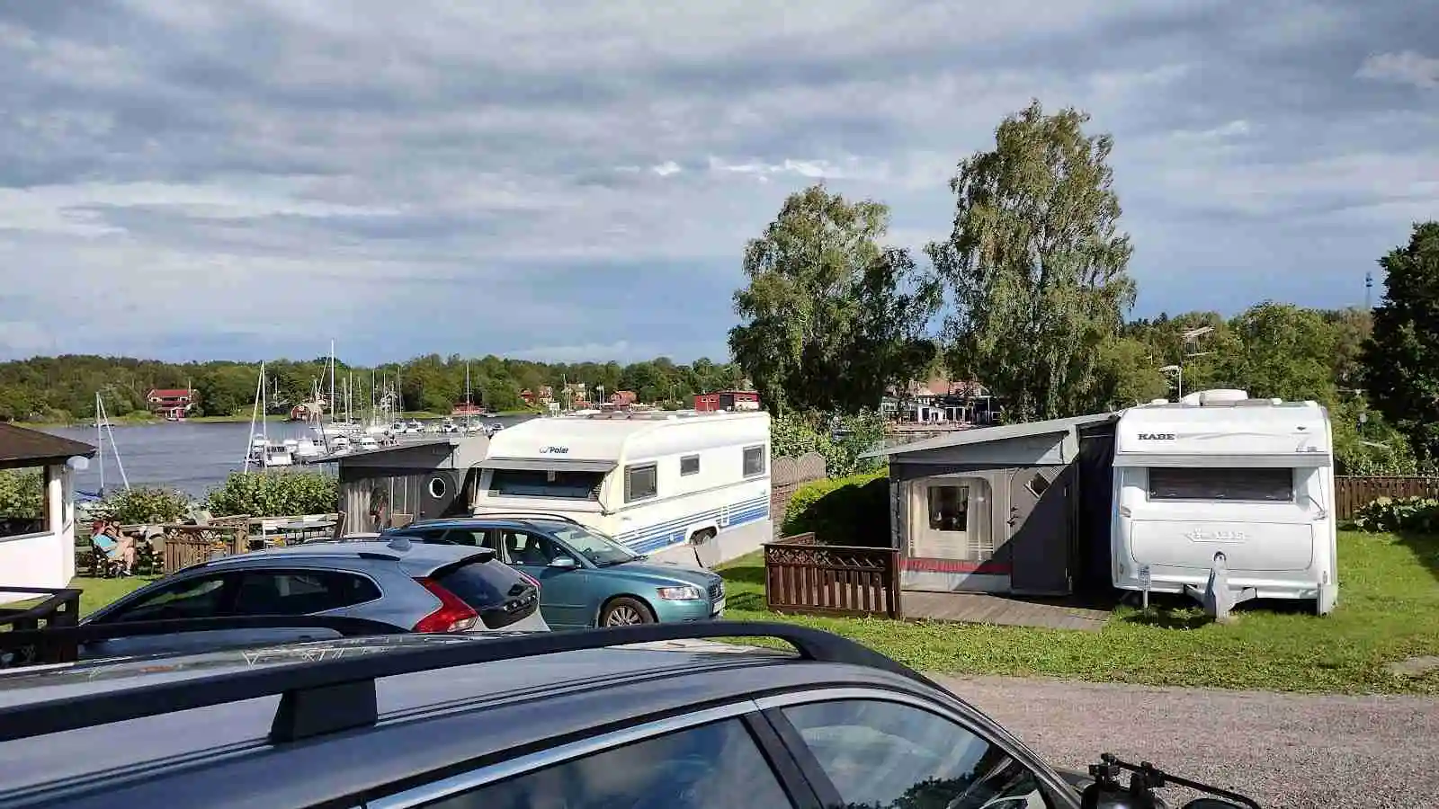 En campingplats med parkerade bilar, däribland familjebilar och lyxfordon, på Norrtälje Camping.
