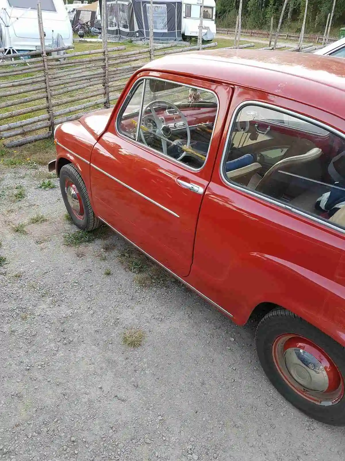 En campingplats med ett par bilar parkerade, omgivna av grönska.