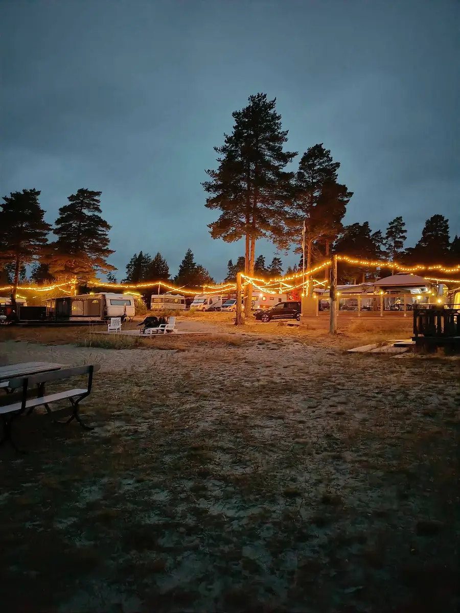 En campingplats vid Ava havsbad i solnedgången, med ett tält och utomhusmöbler i skuggan.