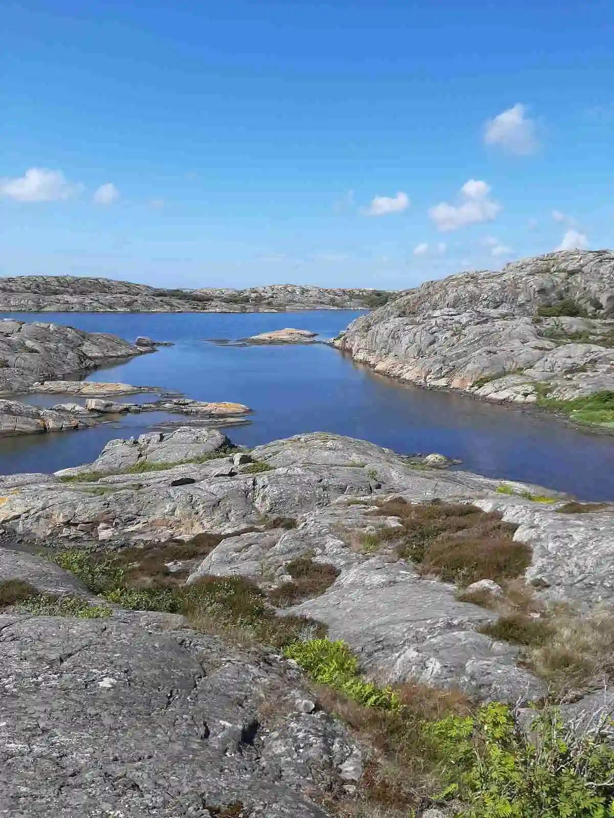 En bild av en karg kustlinje vid Hav & Logi Skärhamn, med klippformationer och utsikt över ett stilla vattenlandskap.