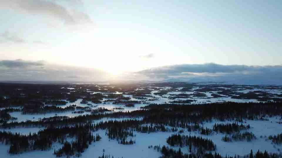 En naturskön vintervy vid Åkersjöns sportcamping, med ett snötäckt landskap, molnig himmel och horisont i skymningsljus.