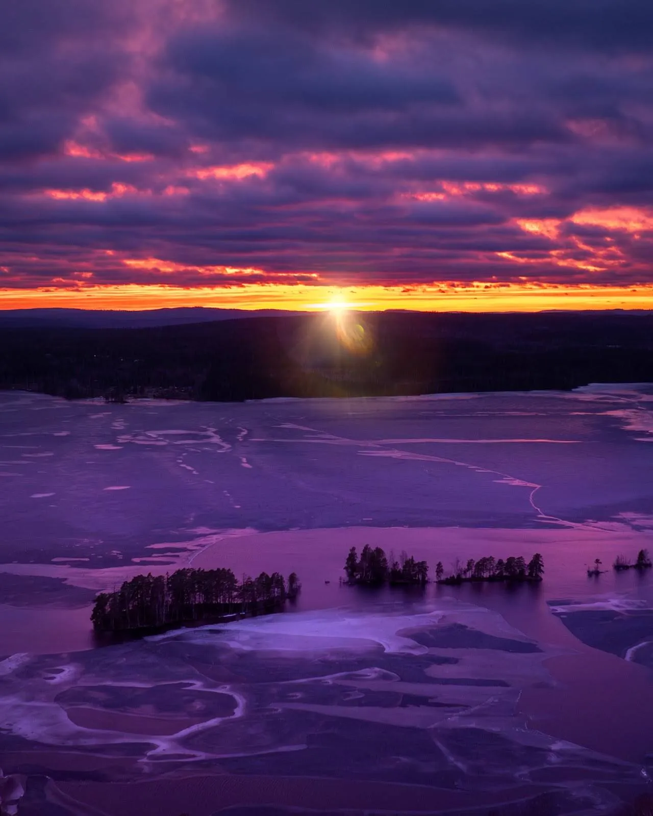 En naturskön vy över Uskavigårdens camping i skymning, med en blå himmel som övergår i varma efterglödande färger vid horisonten. Moln skapar en dramatisk atmosfär medan solen sänker sig.