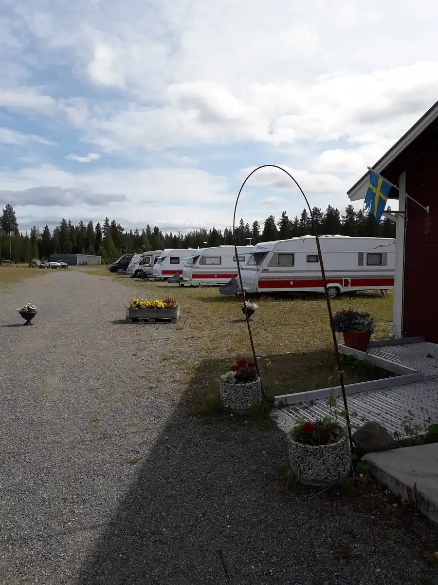 En husbil och en husvagn parkerade på ett öppet område på Fromhedens camping. I bakgrunden syns grönska och träd.