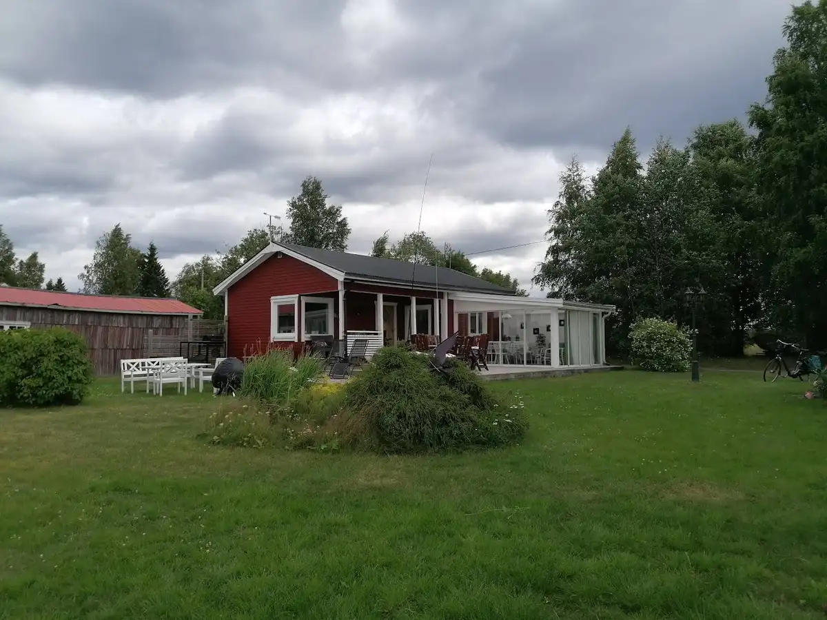En lantlig stuga omgiven av grönska med välskött gräsmatta och små planteringar, typisk för det fridfulla området Klubbensborg.