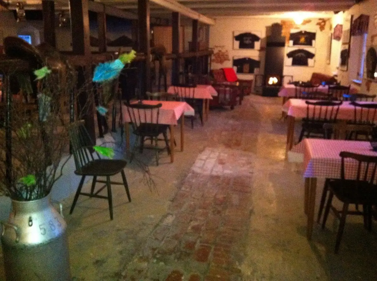 En utomhusmiljö på Hanksville Farm, med trämöbler inklusive ett bord och stolar under ett lätt tak. Bordet är täckt med en duk och inredningen ger en rustik och inbjudande atmosfär, som passar för avkoppling och matupplevelser i det fria.