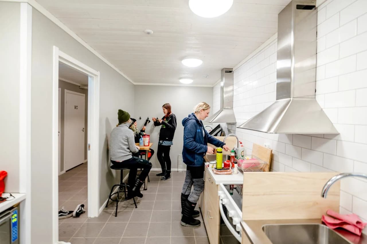 Ett stilrent kök med moderna vitvaror och ljust trägolv. Rummet har en ljus och enkel design med fokus på renlighet och funktionalitet.