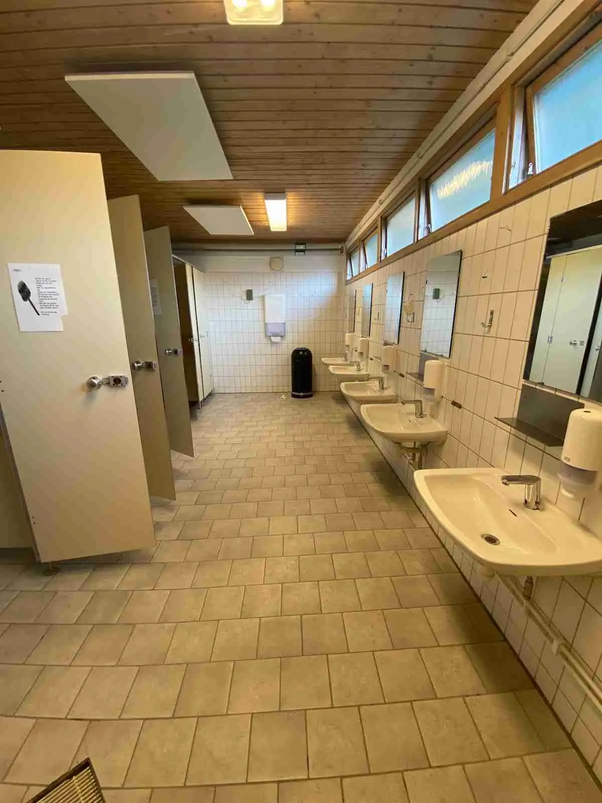 Alt-text: Interiörbild av en träbyggnad på Marstrands familjecamping med trägolv och polerade träytor, inklusive VVS-installationer och designade trädetaljer.