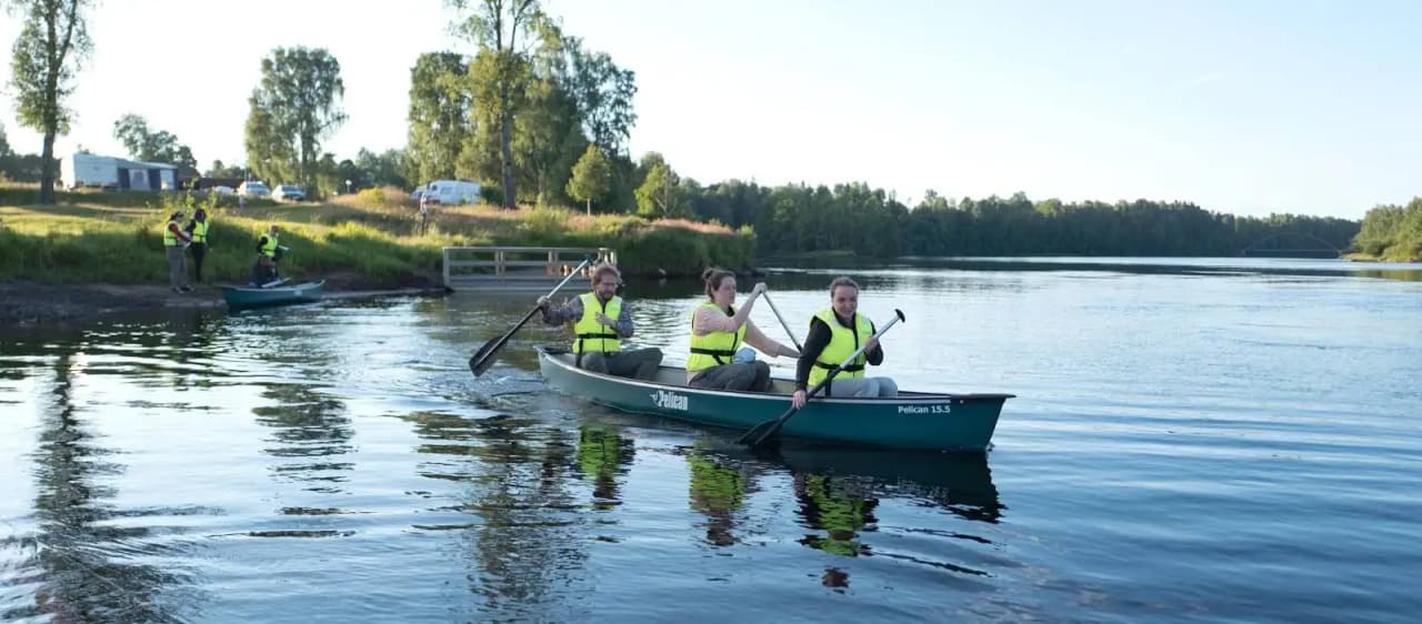 En man paddlar i en kajak på en lugn sjö, omgiven av grönskande natur vid Storängens camping.