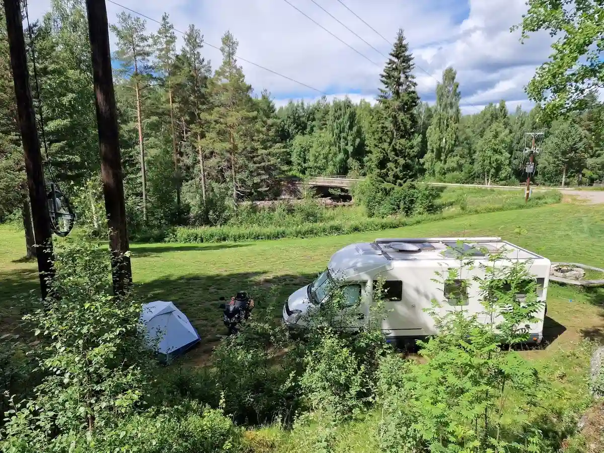 En husvagn står parkerad i en lummig glänta omgiven av skog och träd på Wildlife Sweden Camp Ängra.