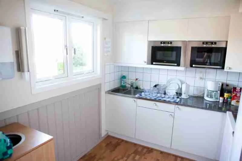 Ett modernt kök i Lisebergsbyn med ljusa trädetaljer, stilrena vitvaror, en diskbänk och rymlig köksbänk. Golvet är av trä och rummet har en minimalistisk inredningsstil.