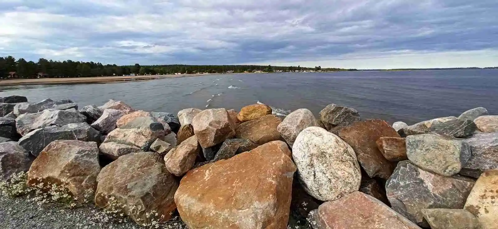 En stenig kuststräcka vid Skellefteå Camping med molnig himmel och ett kustlandskap som sträcker sig ut mot havet.