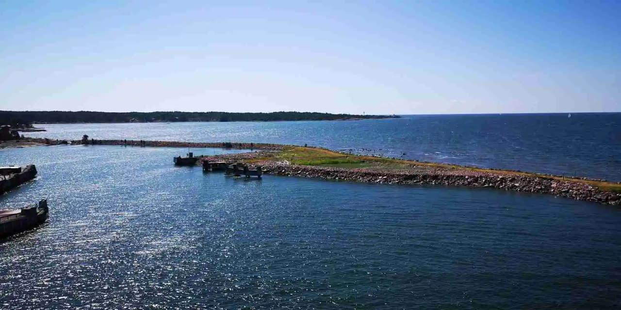 En vidsträckt vy över en kust vid Norrtälje Camping med närliggande vattenresurser som sträcker sig mot horisonten.