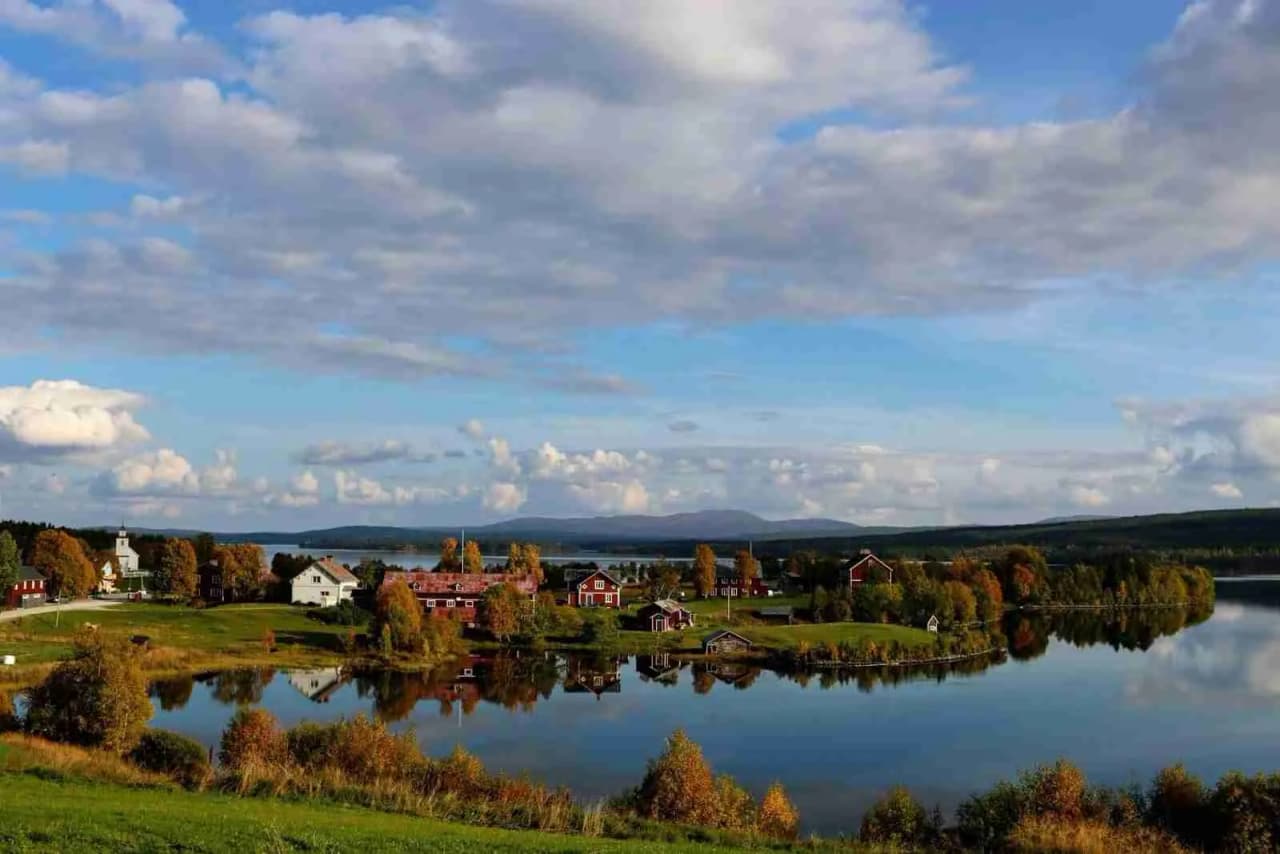 En naturskön vy över en sjö med omgivande grönska vid Storsjö camping och ställplats.