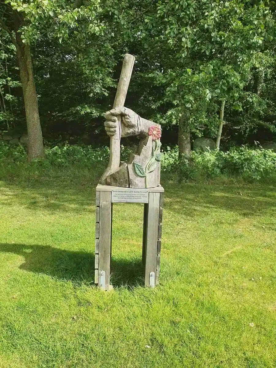 En grönskande park vid Luhrsjöbadens camping pryds av en trästaty och omgivande gräsytor.