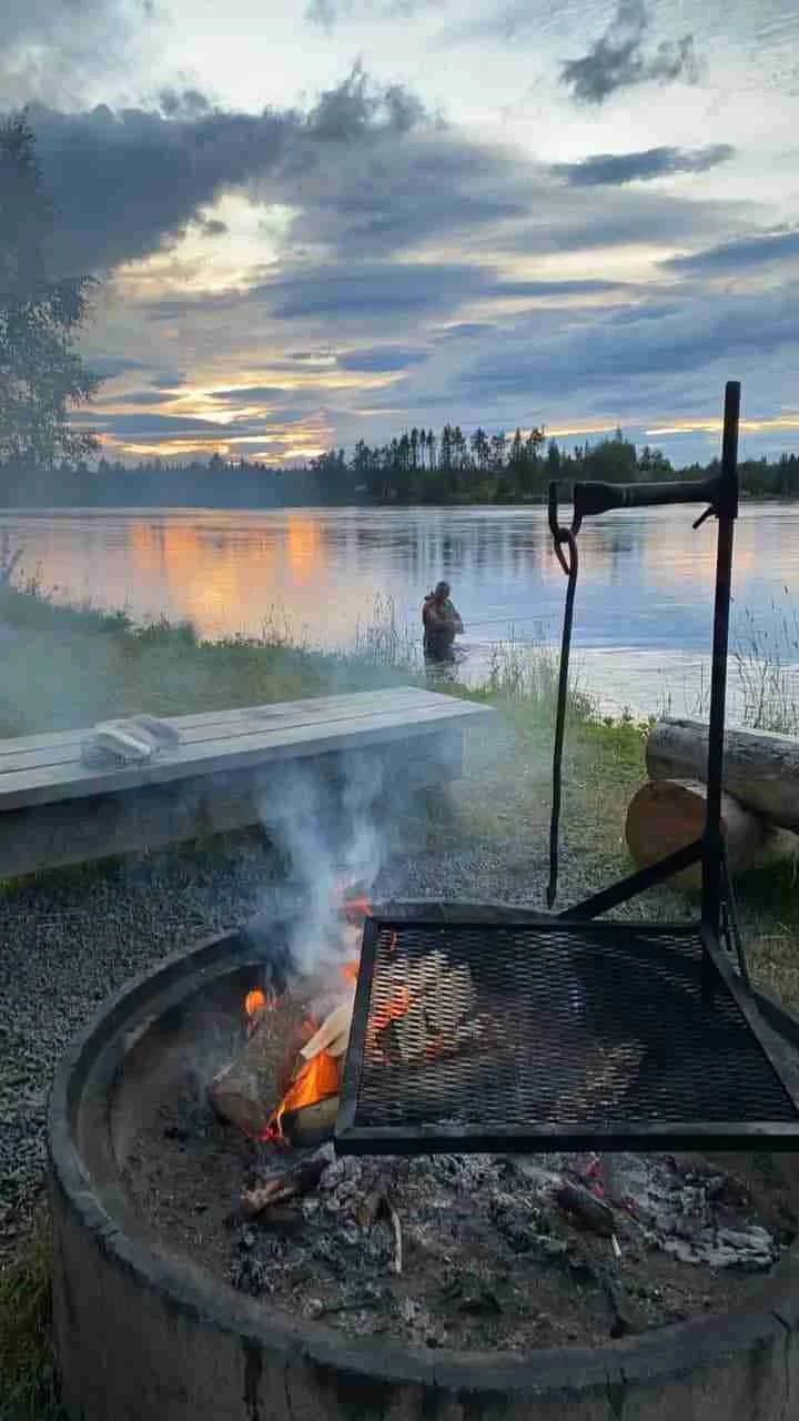 En sjö vid Kvissleströmmens fiskecamping under kvällstid, med speglingar i vattnet och ett varmt sken i horisonten, omgiven av lugna, natursköna omgivningar.