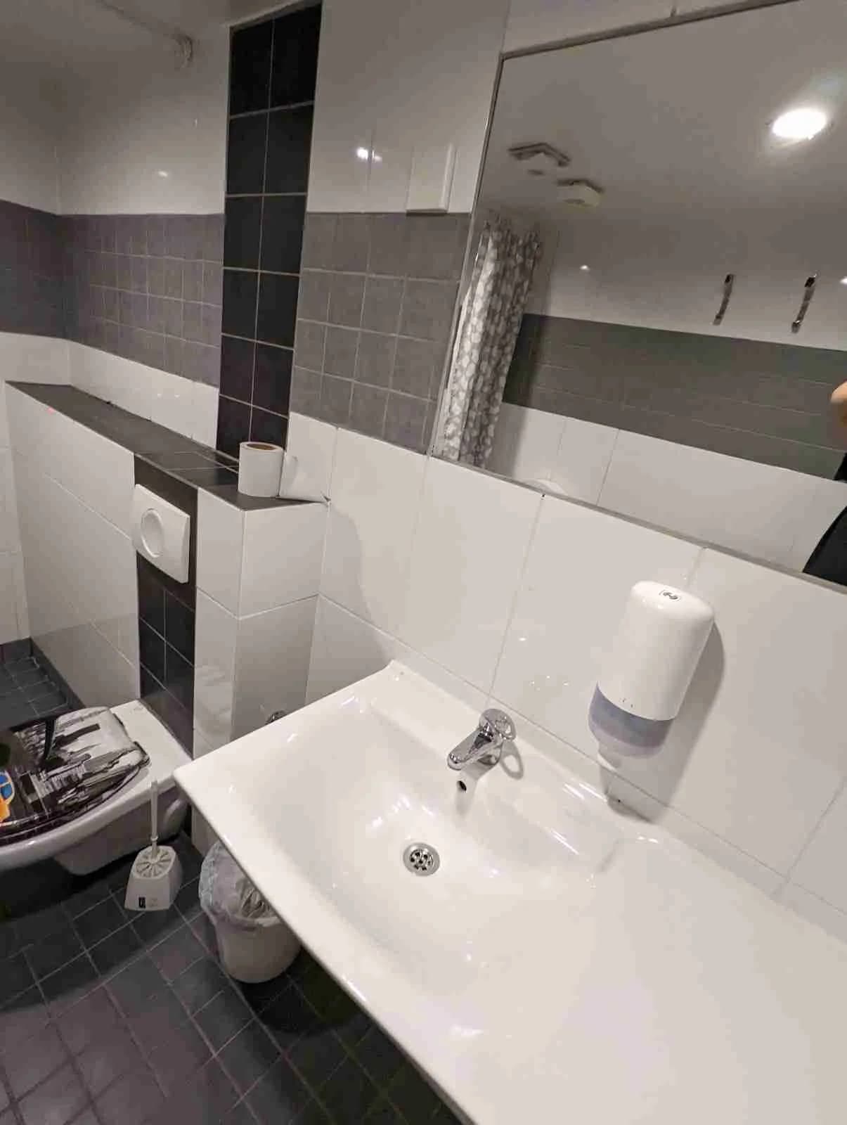 Bild av ett badrum på Fredriksbergs kursgård-camping med kaklade väggar, ett handfat med blandare, och ett kaklat golv.