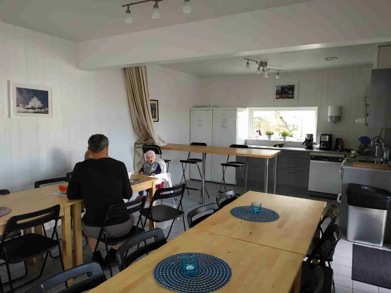 Ett välbelyst rum med ett matbord omgivet av stolar, stilrent inrett med ljusa trägolv och modern belysning, på besöksmålet Hav & Logi Skärhamn.