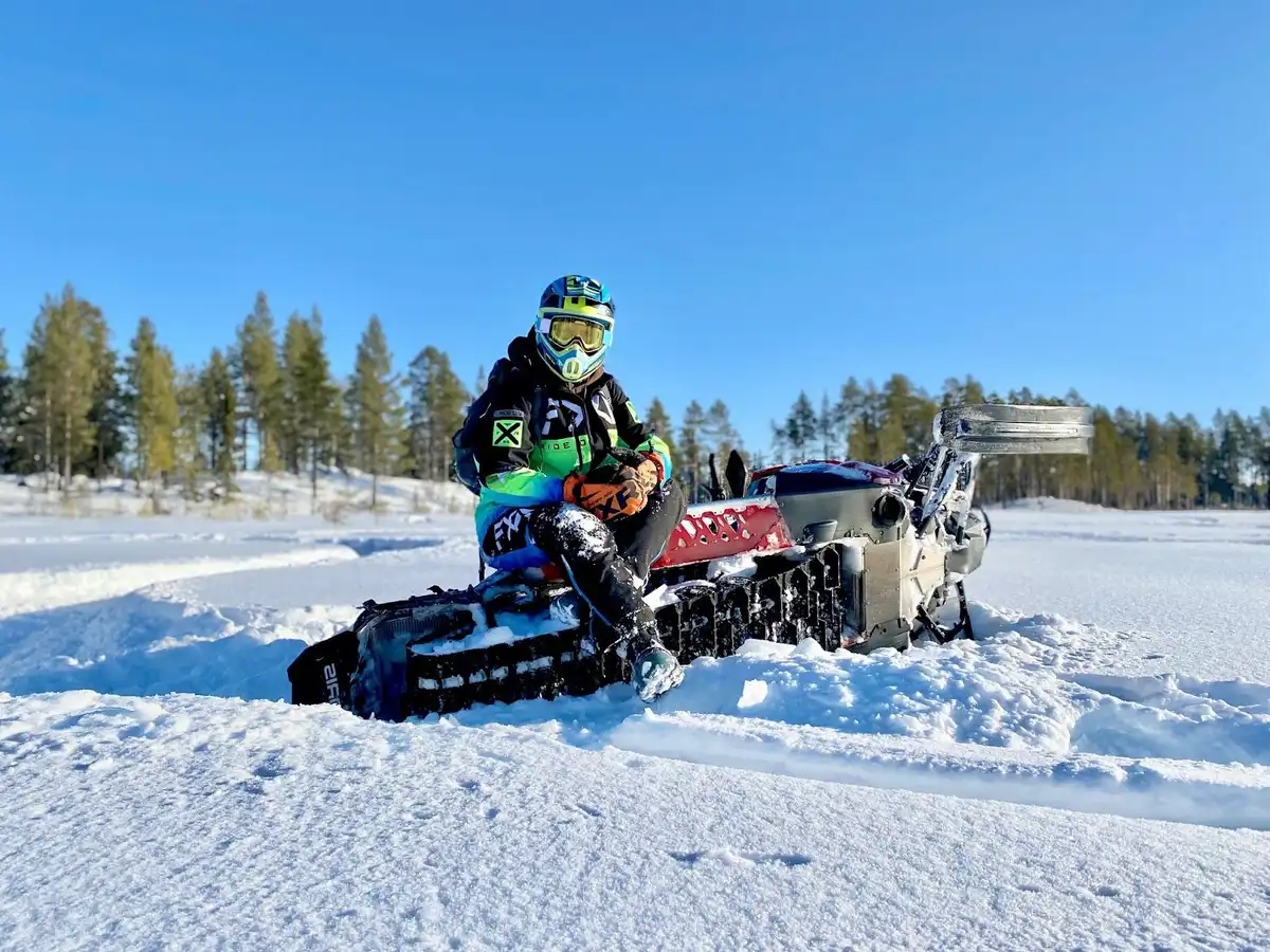 En snöskoter kör genom ett snöigt vinterlandskap vid offroadcamp. Färden sker i extrem vintermiljö och framhäver äventyrslystna motorsportsaktiviteter på is och snö.