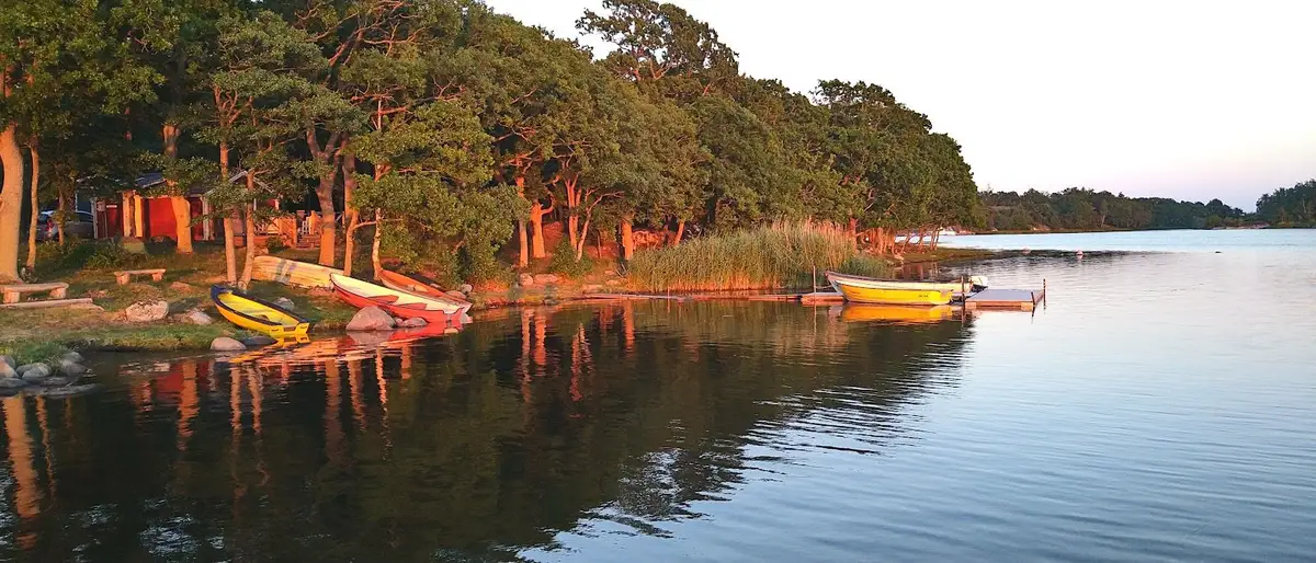 En segelbåt ligger förtöjd vid en brygga på det stilla vattnet en solig sommardag vid Kustgården Senoren.