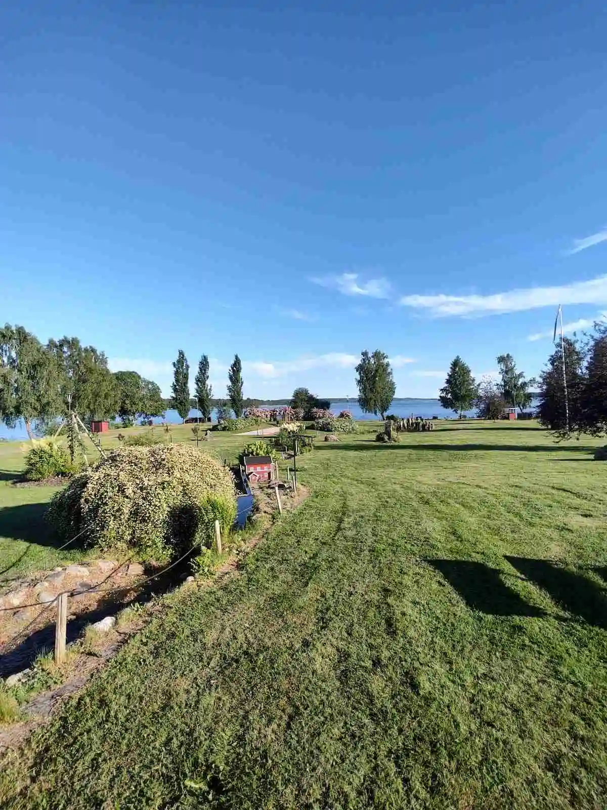 En grön och inbjudande campingplats med välskötta gräsmattor och öppen ängsmark, perfekt för rekreation och avkoppling, belägen i Vegby camping.