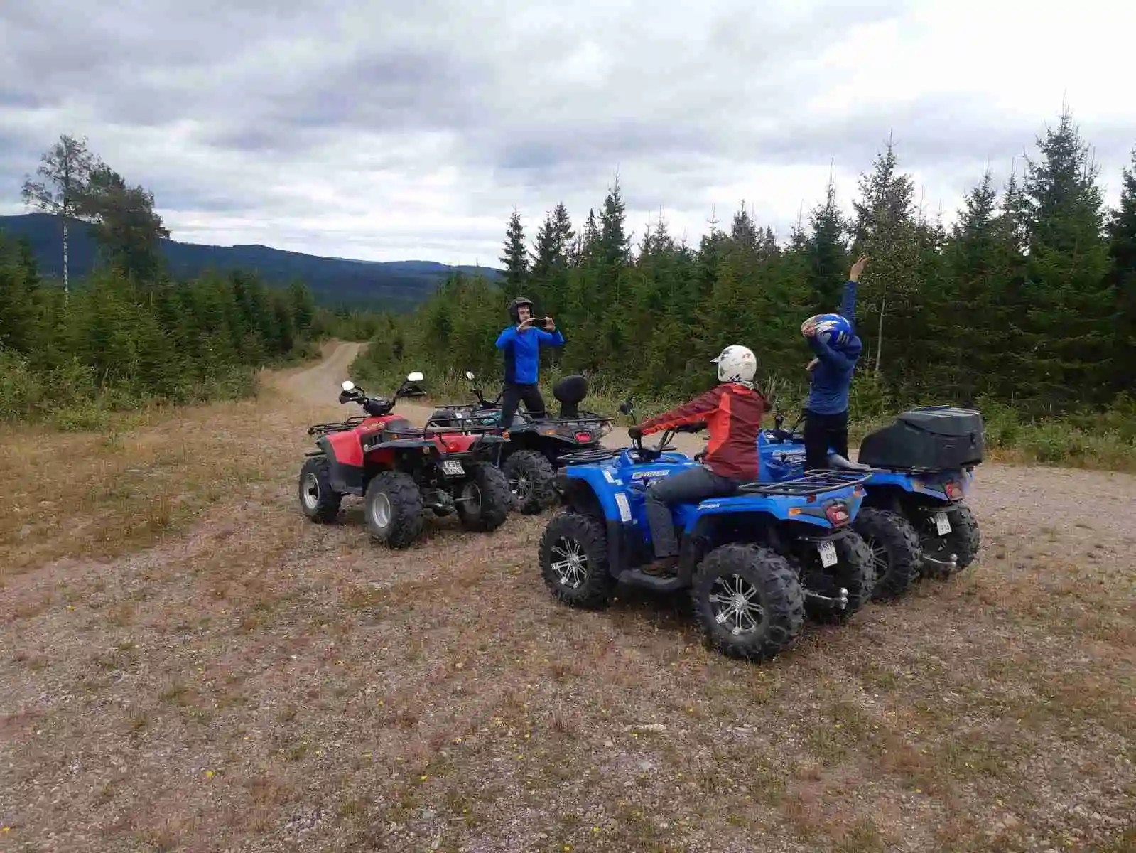 En fyrhjuling parkerad på en campingplats med flera stugor i bakgrunden, omgivet av grönska.